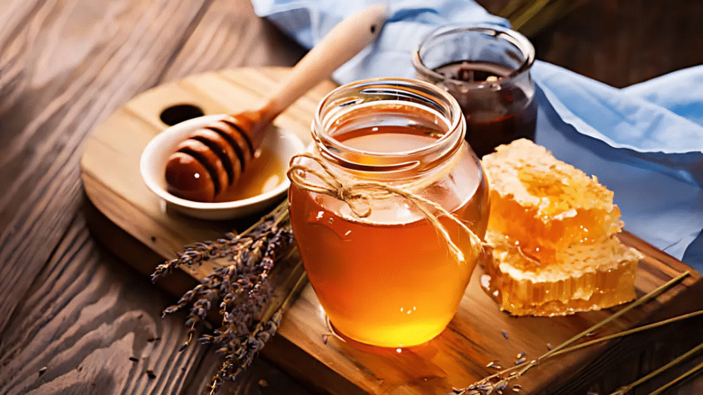 Raw honey in a glass jar with honey dipper and honeycomb on a wooden table, part of a fascinating food example from weird facts about the world.
